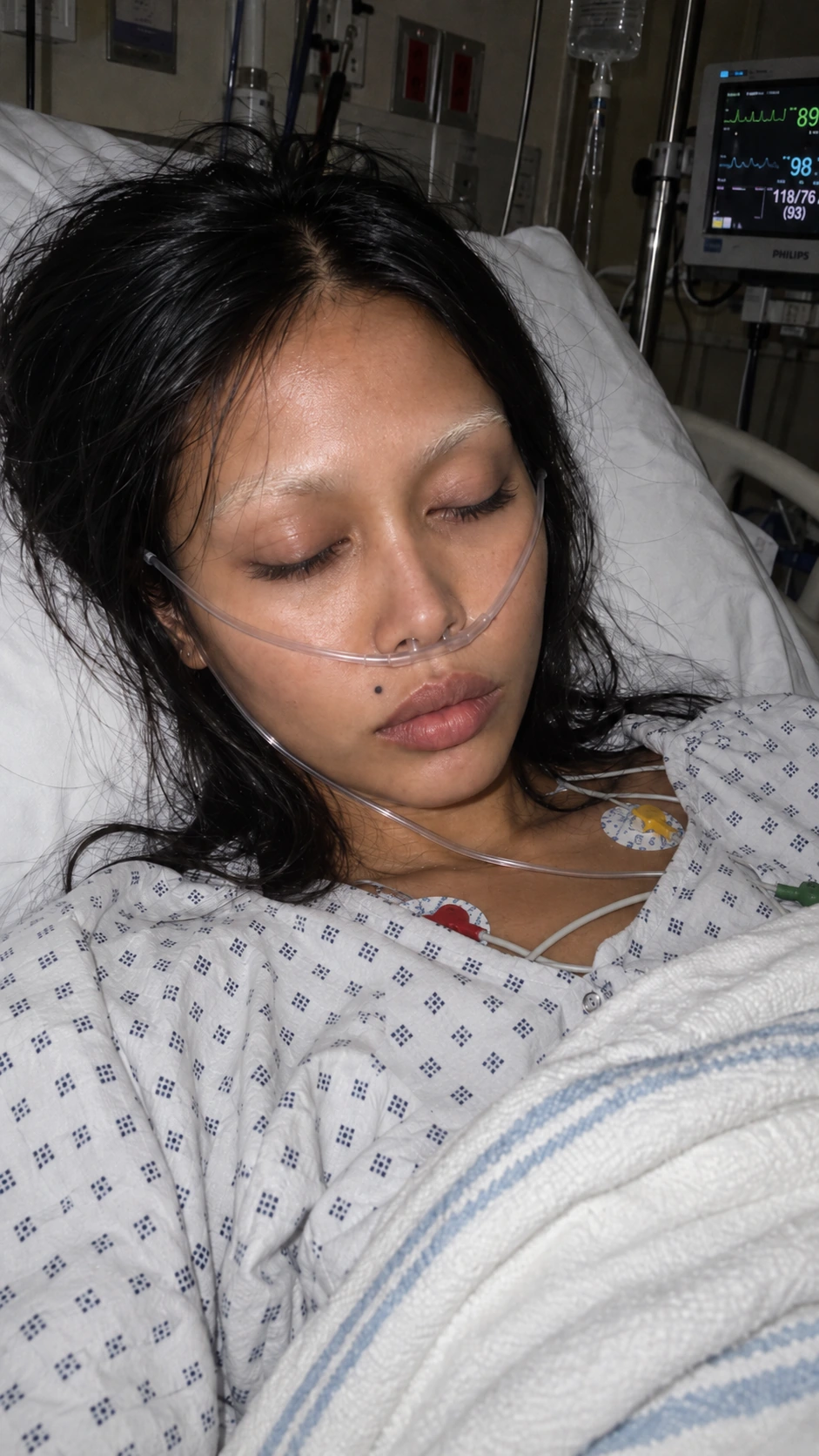 Conceptual self-portrait resting in a hospital bed beneath medical monitors
